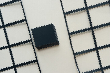 pile of black paper tiles with stamp-like detailing and paper grids