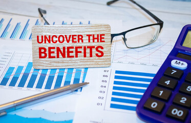 Uncover the Benefits - text written on notebook on wooden table with pen coffee and glasses