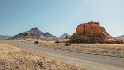 Rast an einem solitären roten Felsen an einer einsamen Straße in der bergigen Landschaft des Damaralandes, Namibia