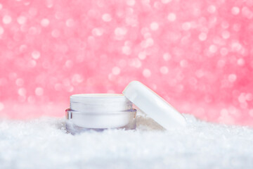 Cosmetic cream in white jar. Skin care for face and hands. Viva magenta bokeh background. Winter skincare concept. Color of the year 2023