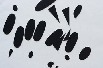 black paper ovals or shapes on blank paper