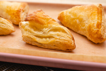 Apple turnover close-up on a baking sheet on the table, just from the oven, rustic background