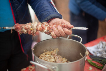 Putting meat on knife. Cooking meat with your hands. Street food. Folk Caucasian cuisine.