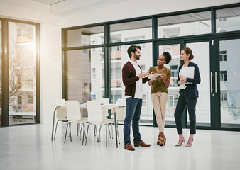 Fototapeta premium Rolling out a quick update to the team. Shot of a group of colleagues having a meeting in a modern office.