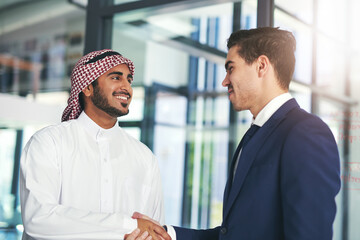 Business built on a mutual purpose. Shot of a young muslim businessman shaking hands with an...