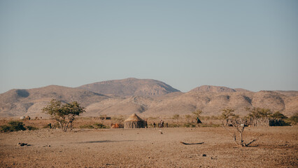 Blick auf ein Himba-Dorf in der kargen Landschaft des Kaokovelds, Kunene, Namibia