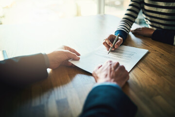 Going through the terms of their contract. Closeup shot of two unrecognizable businesspeople going...