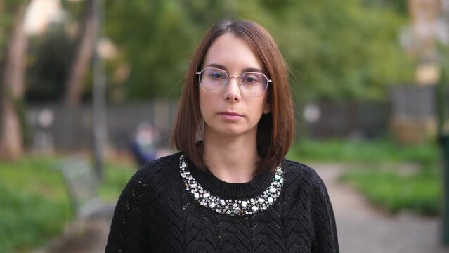 serious young woman at park stares at the camera thoughtfully