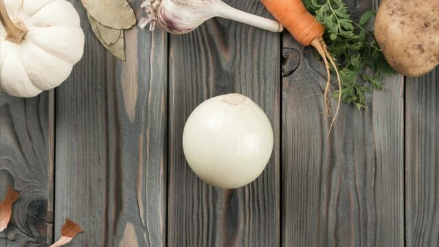 Peeling spicy white onion. Stop motion, flat lay. Fresh raw vegetables. Skinning, rinding on kitchen wooden table. Prepare ingredients for cooking, recipe. Healthy diet, food waste.