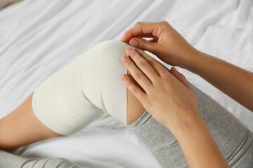 Young woman with leg wrapped in medical bandage on bed, closeup