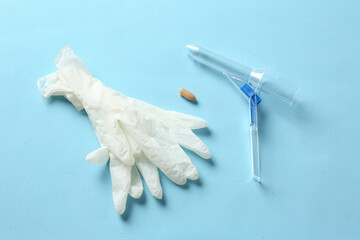 Anoscope, suppository and rubber gloves on light blue background, flat lay. Hemorrhoid treatment