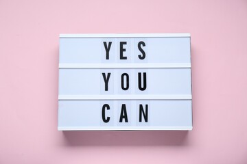 Lightbox with phrase Yes You Can on pale pink background, top view. Motivational quote