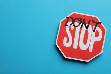 Don't stop - motivational phrase. Road sign sticker with added written text on light blue background, top view - obrazy, fototapety, plakaty