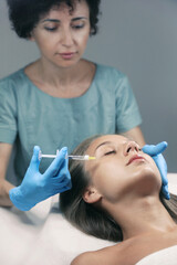 Beautiful woman getting facial injection in salon