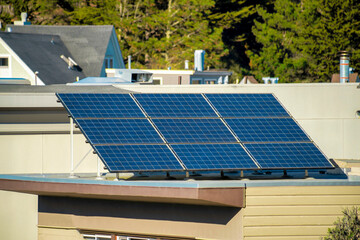 Solar pannel on top of building with flat roof and beige or brown exterior of building in the suburban neighborhood downtown