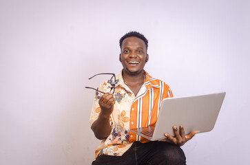 Excited black African male student using laptop holding glasses in hand
