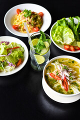 Lunch set made of chicken soup, salad,pasta carbonara, lemonade on black background