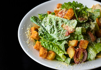 Caesar salad served in Vietnamese style on black background side view with copy space
