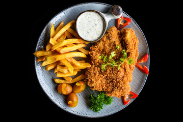 pork chop steak with vegetables on blue plate isolated on black background side view