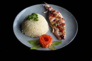 Grilled squid with white rice on blue plate isolated on black background side view 
