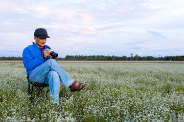 Photographer sits on a chair in the meadow.