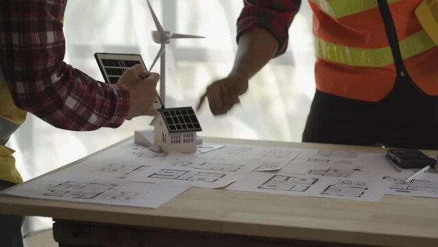 Architects, engineers, blueprints for alternative energy wind turbine installation planning, meeting to discuss wind power generation and wind turbine installation in the meeting room.