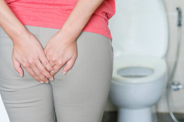 The concept of constipation. The woman's hand is holding a toilet paper. Stained Toilet bathroom background