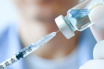 doctor's hand holds a syringe and a blue vaccine bottle at the hospital. Health and medical...