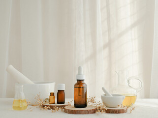 Essential oil bottle with white dropper decorate with natural wooden stand and flower on white curtain background. skincare and spa concept.