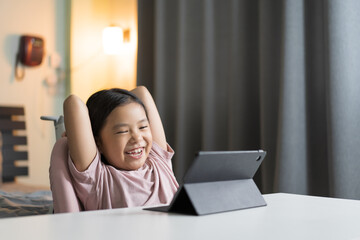 asian child smile learning on computer tablet or kid girl student enjoy fun to study online class or person happy learn from home school by video call studying technology education on pad in bedroom