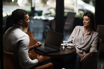 Friends at a cafe after work. Business colleagues working on laptop and drinking coffee in a restaurant..