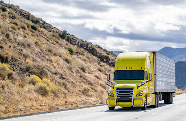 Bonnet bright yellow big rig semi truck tractor transporting frozen cargo in reefer semi trailer...