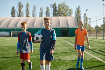 Portrait of serious young soccer player standing on field with teammates