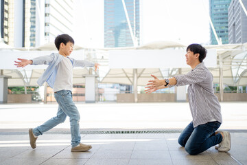 Happy cheerful Asian little boy running to his father at the railway or sky train station after his...