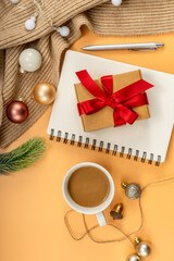 Coffee, Gifts, notepad and christmas decorations on yellow table. Christmas or new year concept. Flat lay, top view.