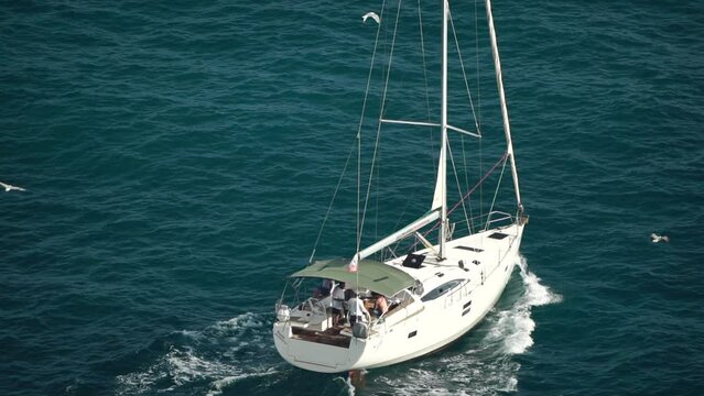Rear view of a white yacht sailing on a deep blue sea with white waves.