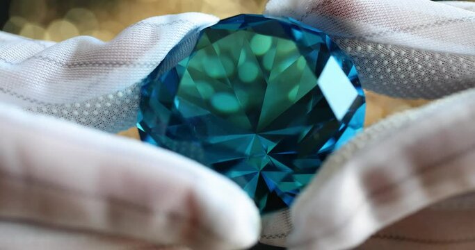 Blue diamond gemstone holding in gloves closeup