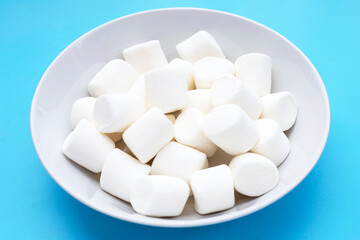 Fototapeta na wymiar White marshmallows on blue background.