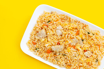 Fried rice in white plate on yellow background. Top view