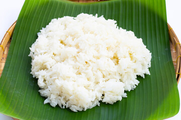 Sticky rice on banana leaf in bamboo basket on white background.