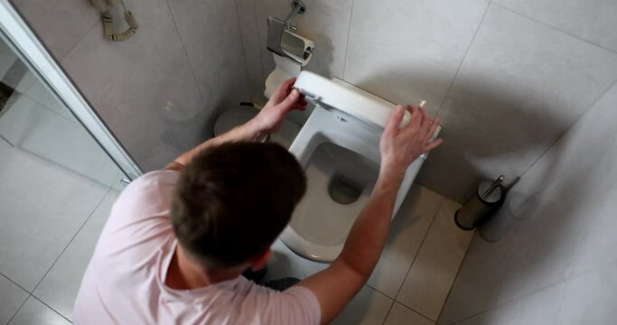 Man on his knees in bathroom vomits into toilet
