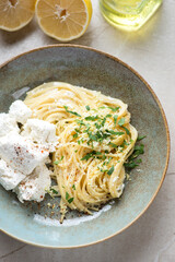 Closeup of spaghetti with ricotta cheese and lemon zest in a rustic plate, vertical shot, high angle view