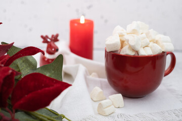 Fototapeta na wymiar Red winter marshmallow mug with lighted candle on white background