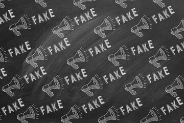 Pattern from megaphone icons and lettering FAKE drawn in chalk on a blackboard. Concept of announce, media, information and disinformation. Fake news.