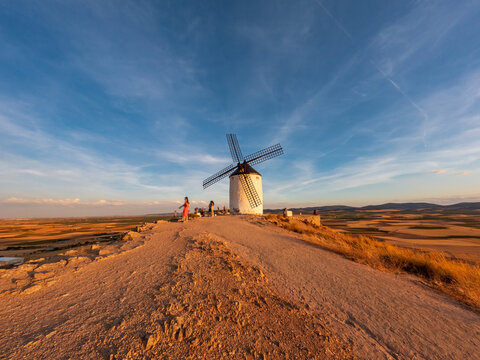 Ancient windmill at sunset with blurred tourists