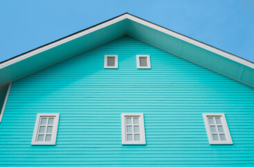 house with a decorative aquamarine color wooden wall panel and white window in worm eye view