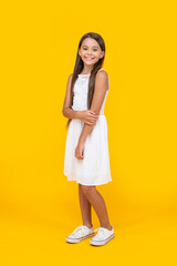 glad teen girl in white dress standing on yellow background