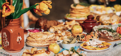 Dishes of the traditional Belarusian cuisine - pancakes, pancakes with caviar, lard, bacon, honey and pickled cucumbers. Attribute of traditional folk celebration of Maslenitsa. Panorama, Panoramic