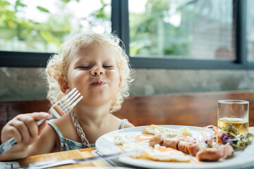The child is happy to eat food from a plate with an emotion of joy and happiness. Very tasty and fun.