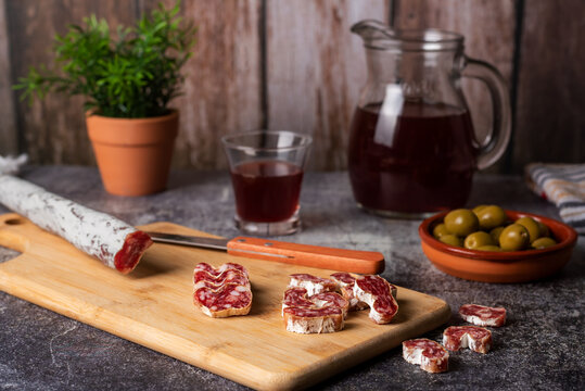 Fuet, Espetec, Secallona or Petador, typical Catalan sausage spread throughout Spain based on pork, bacon and pepper, accompanied by a jug and a glass of red wine, close-up.